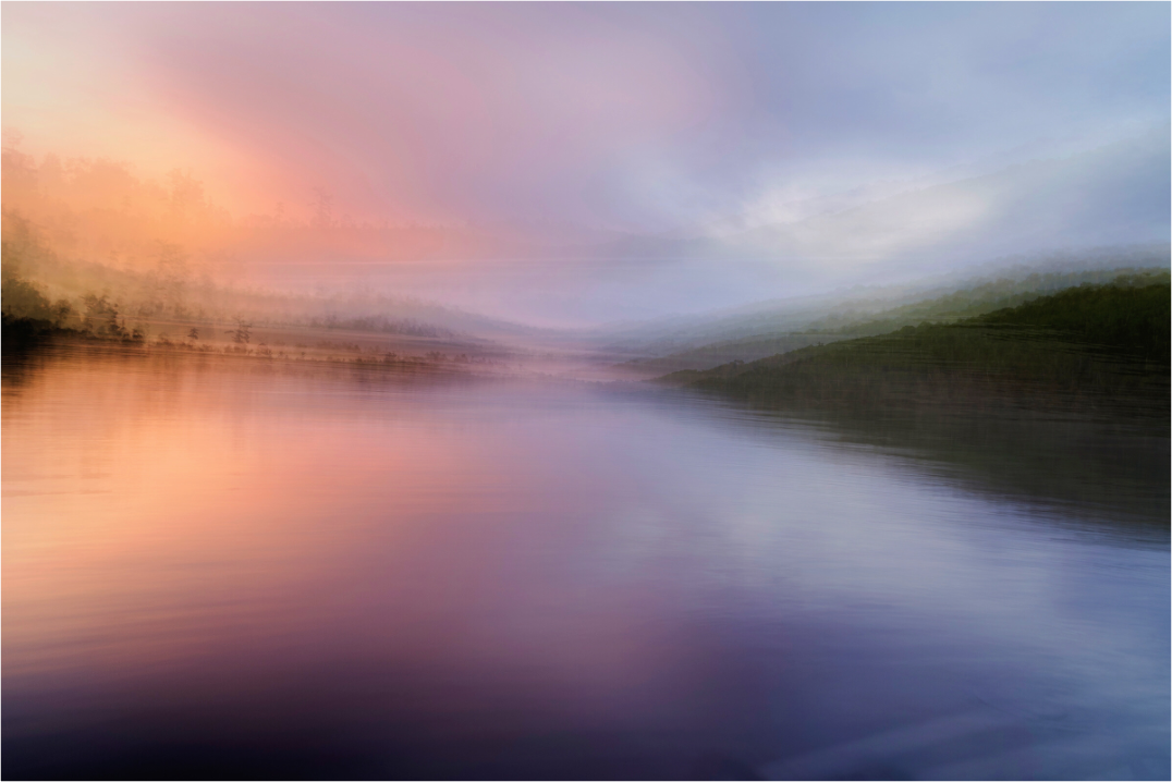 Boundary Waters at sunset — warm light dissolving into still water and a distant treeline