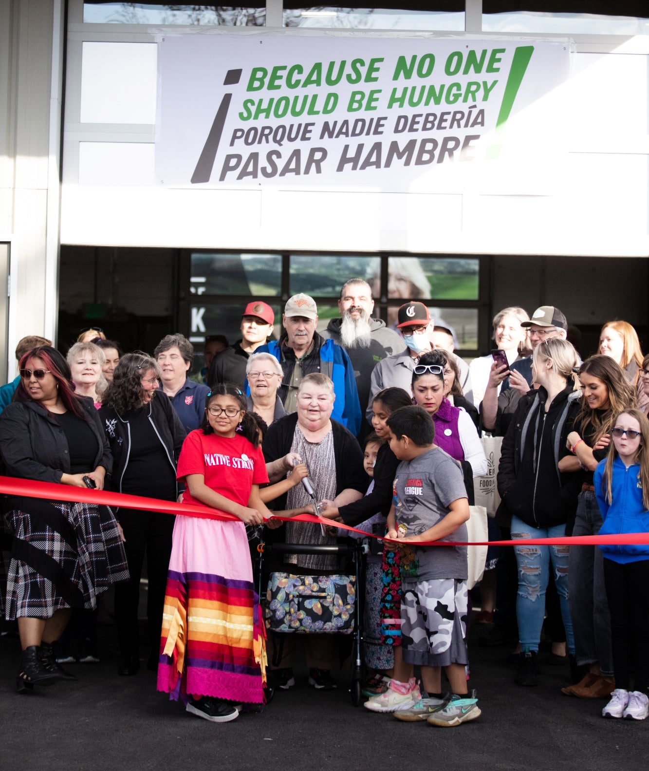 Group of people at a ribbon-cutting ceremony in front of a building with a hunger awareness banner. Event photographer at Columbia River Gorge, Oregon