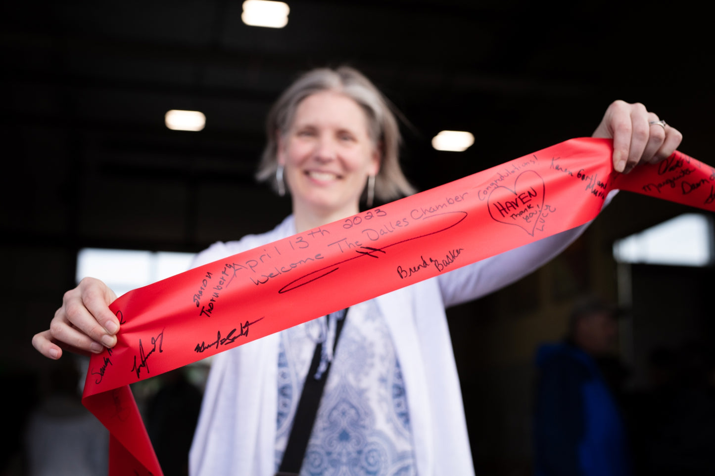 Person holding a red ribbon with signatures in an indoor setting. Event photographer at Columbia River Gorge, Oregon