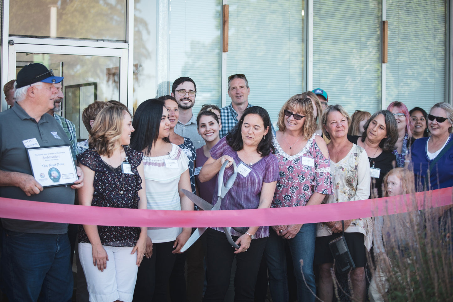Group of people at a ribbon-cutting ceremony in front of a building. Event photographer at Columbia River Gorge, Oregon