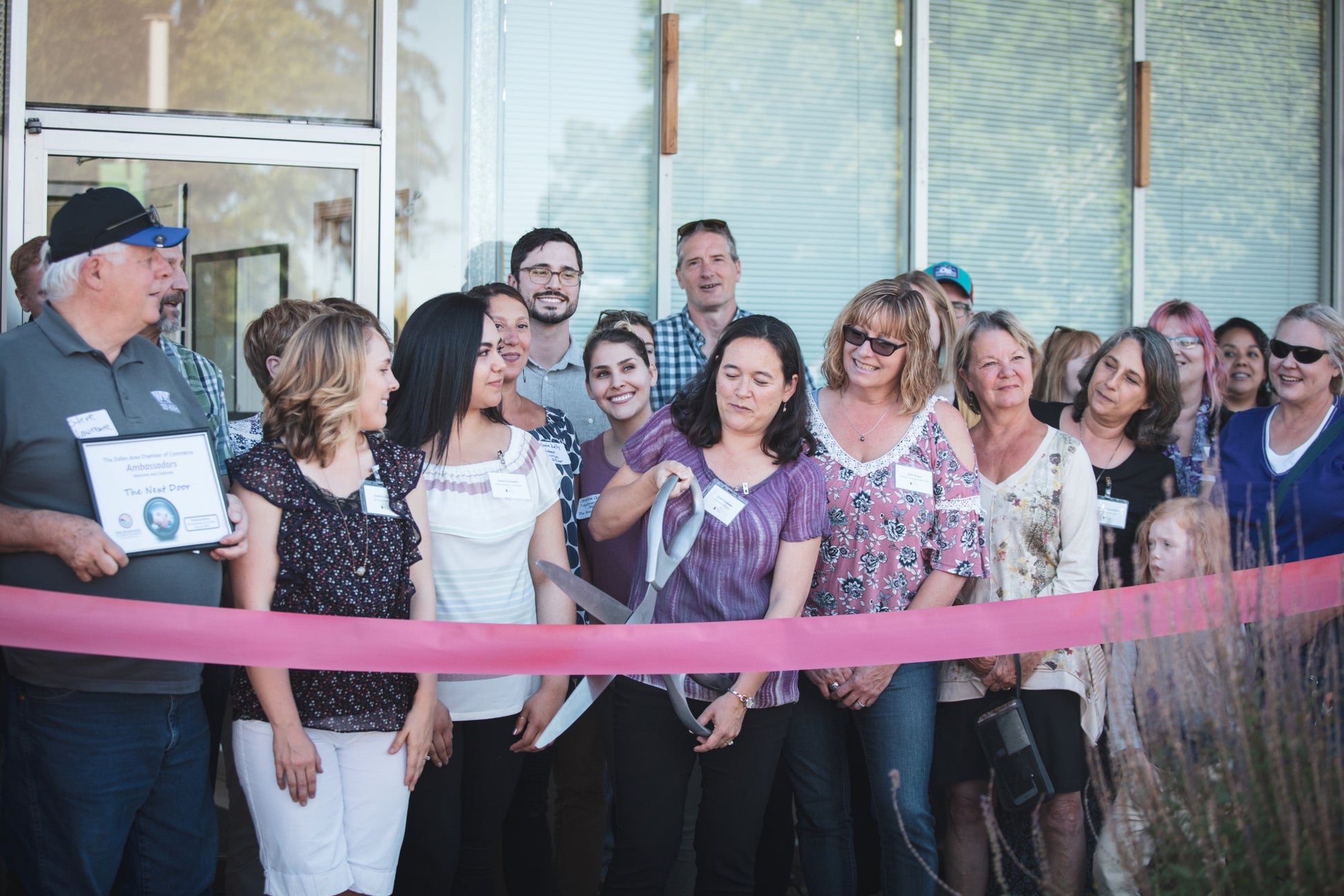 Group of people at a ribbon-cutting ceremony in front of a building. Event photographer at Columbia River Gorge, Oregon