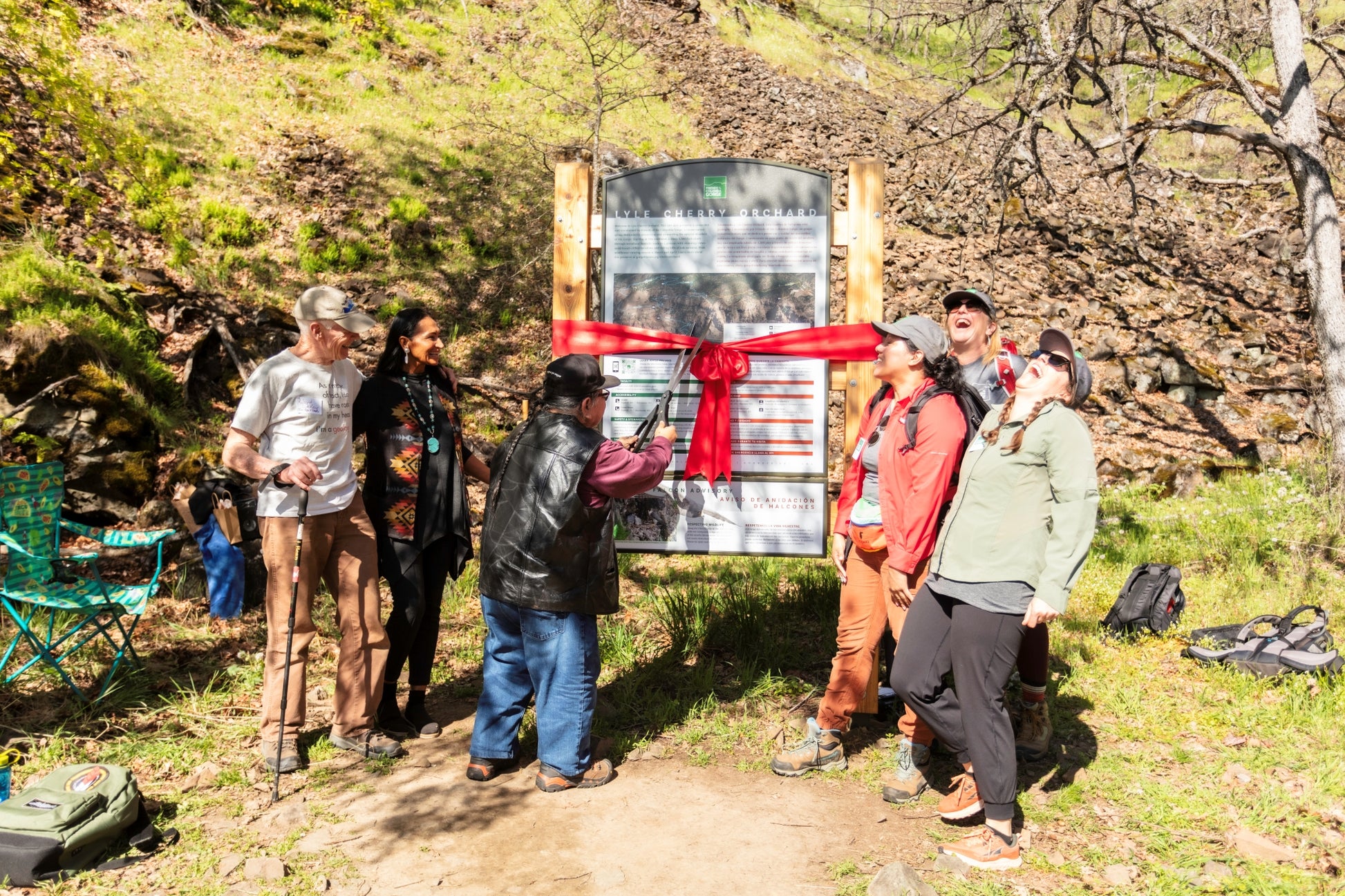 Group of people at a ribbon-cutting ceremony for a trail sign in a forest setting. Event photographer at Columbia River Gorge, Oregon
