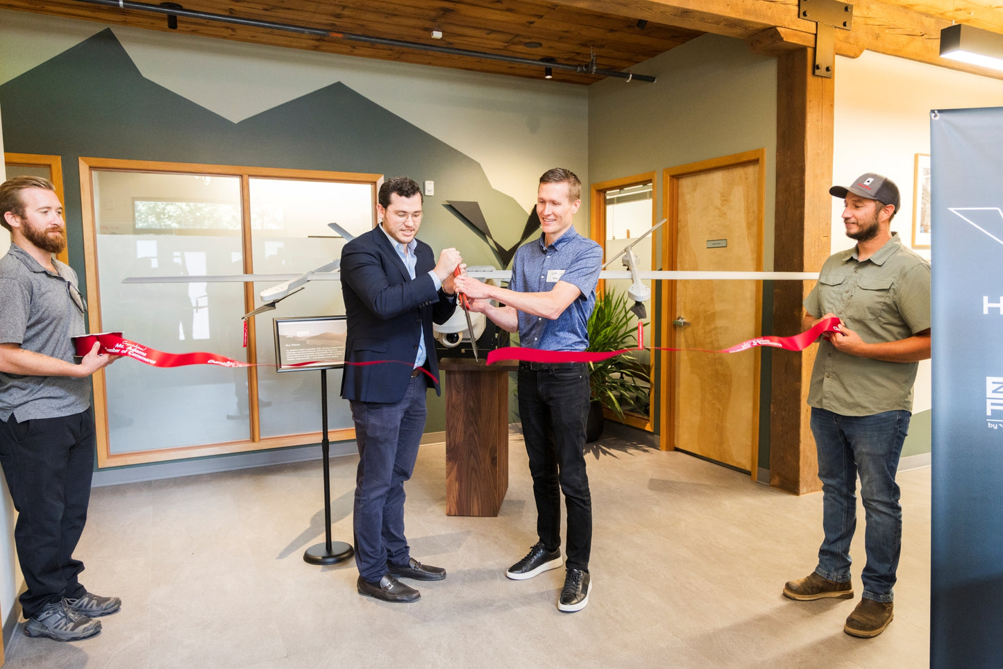 Four men participating in a ribbon-cutting ceremony in an indoor setting. Event photographer at Columbia River Gorge, Oregon