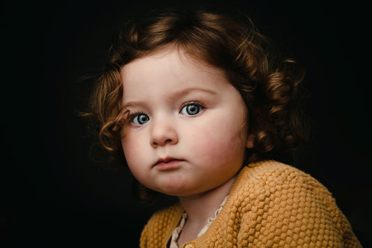 Child wearing a yellow sweater against a dark background.  Minimalist portrait mini session, Hood River Oregon photographer 