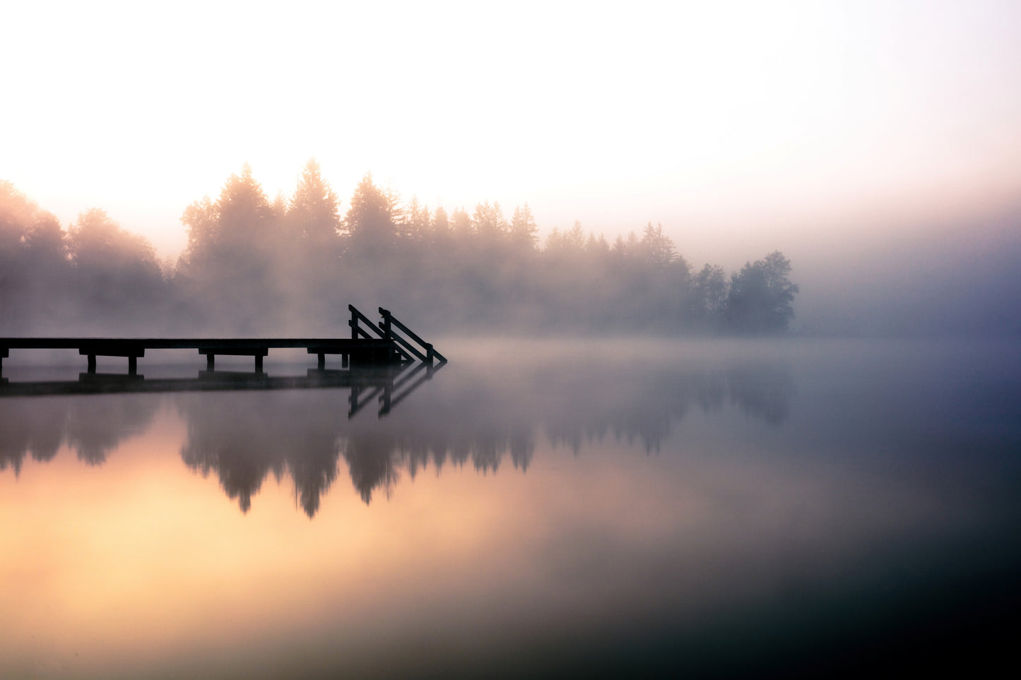 Misty sunrise at Kirchsee lake dock in Oberbayern Bavaria Germany with swimmers in fog